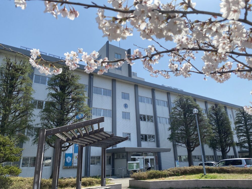 4階建ての白い校舎の手前には、満開の桜